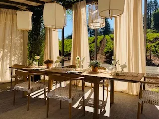 An outdoor table set for lunch under linen curtains and paper lanterns at a Napa winery